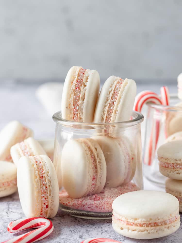 A few peppermint macarons in a small glass jar surrounded by more macarons
