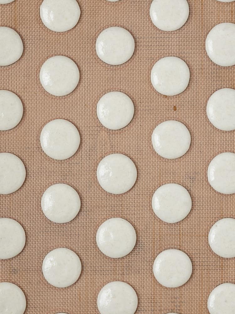 Macarons piped onto a baking sheet