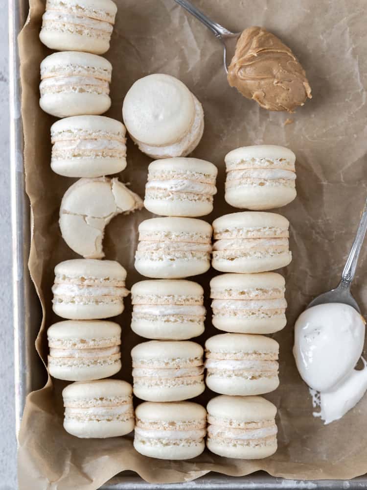 Looking down on three rows of macarons next two a spoonful of marshmallow fluff and a spoonful of creamy peanut butter