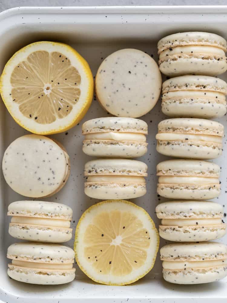 Looking down at a tray full of french macarons and cut lemons