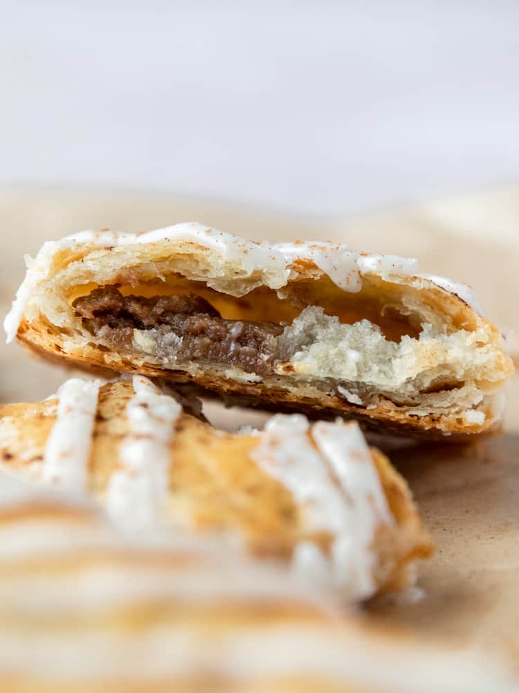 A pop-tart that is cut open, showing the flaky crust and cinnamon roll filling. 