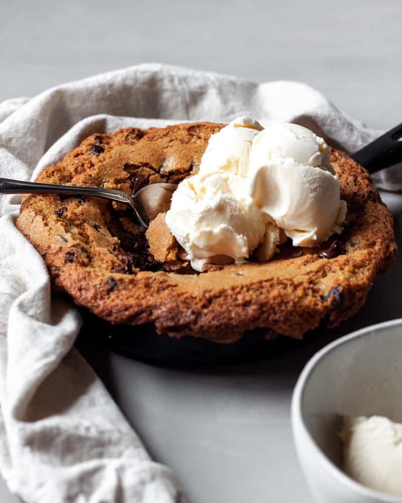 A stuffed chocolate chip skillet cookie topped with ice cream