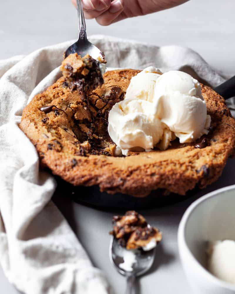 A skillet cookie with a spoonful being taken out of it