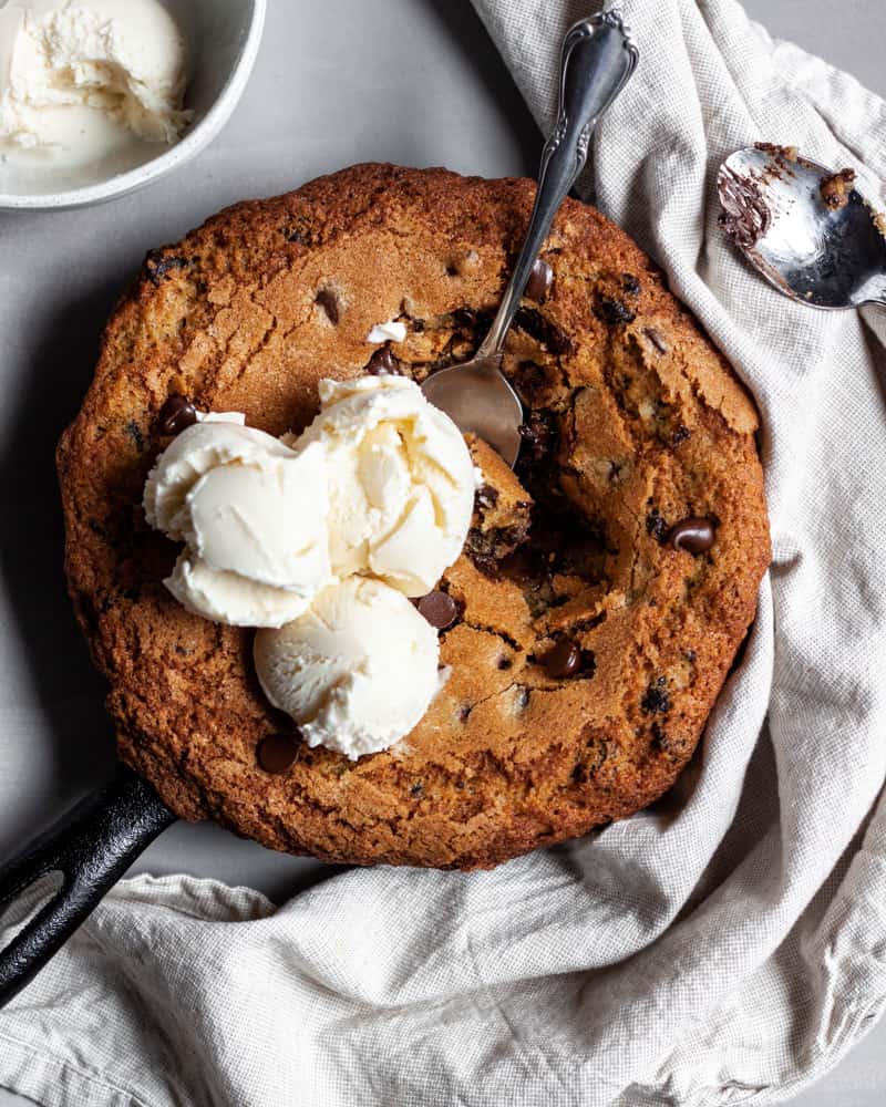 Looking down on a stuffed chocolate chip skillet cookie with three scoops of ice cream on top