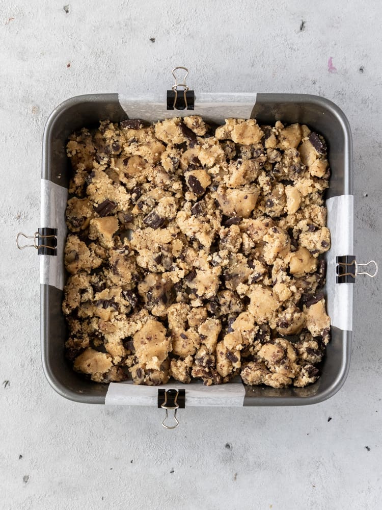 The cookie dough broken into chunks and placed in the prepared pan
