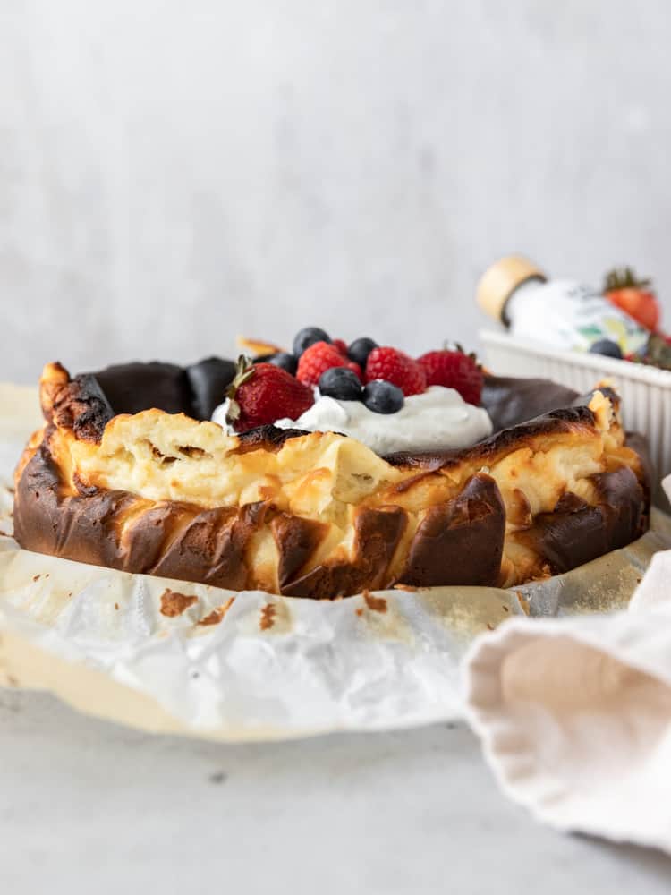 A whole basque cheesecake topped with whipped cream and berries