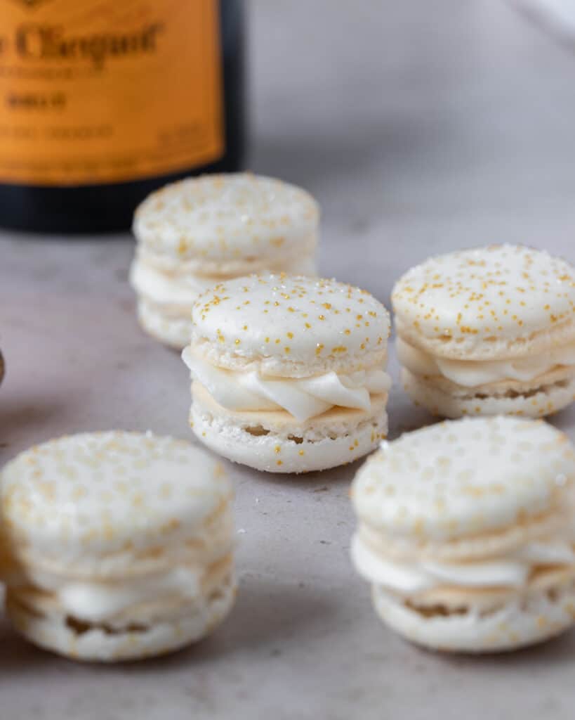 a close up of a macaron topped with sprinkles and filled with champagne buttercream
