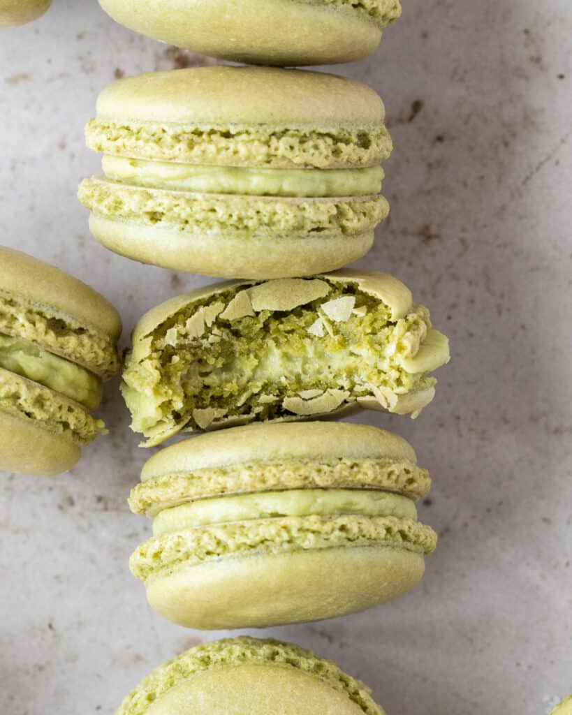 a close up of a matcha macaron with a bite out of it