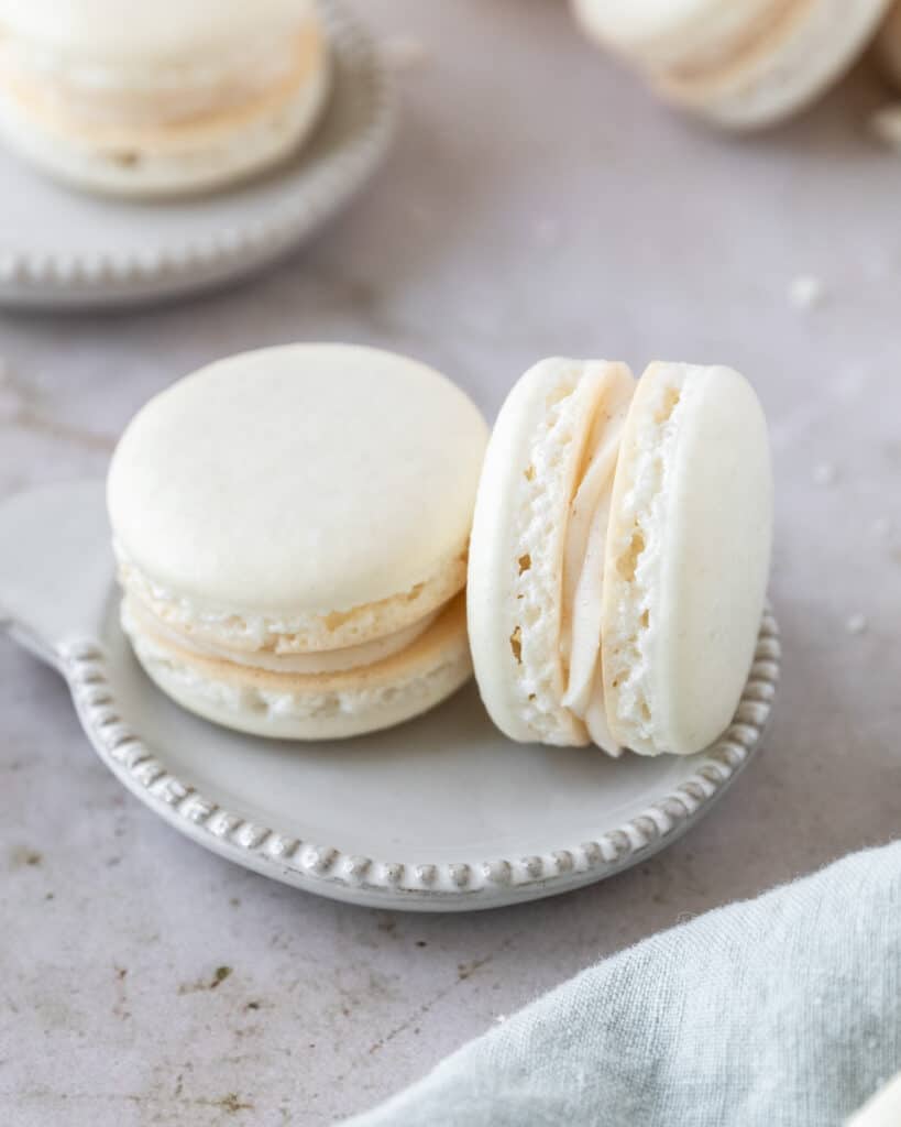 a close up of two brown butter macarons on a small plate