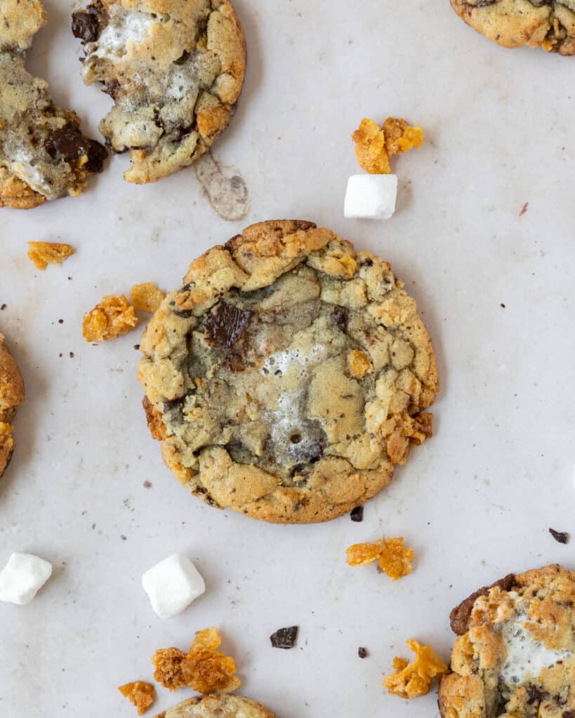 looking down on a cornflake crunch cookie surrounded by chocolate, marshmallows, and cornflakes