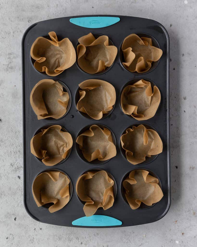 a muffin tin lined with parchment paper squares