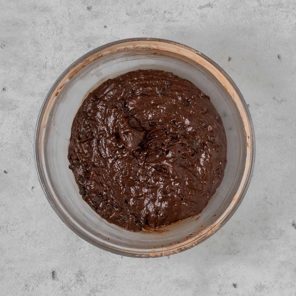 the completed brownie batter in a glass bowl on grey background