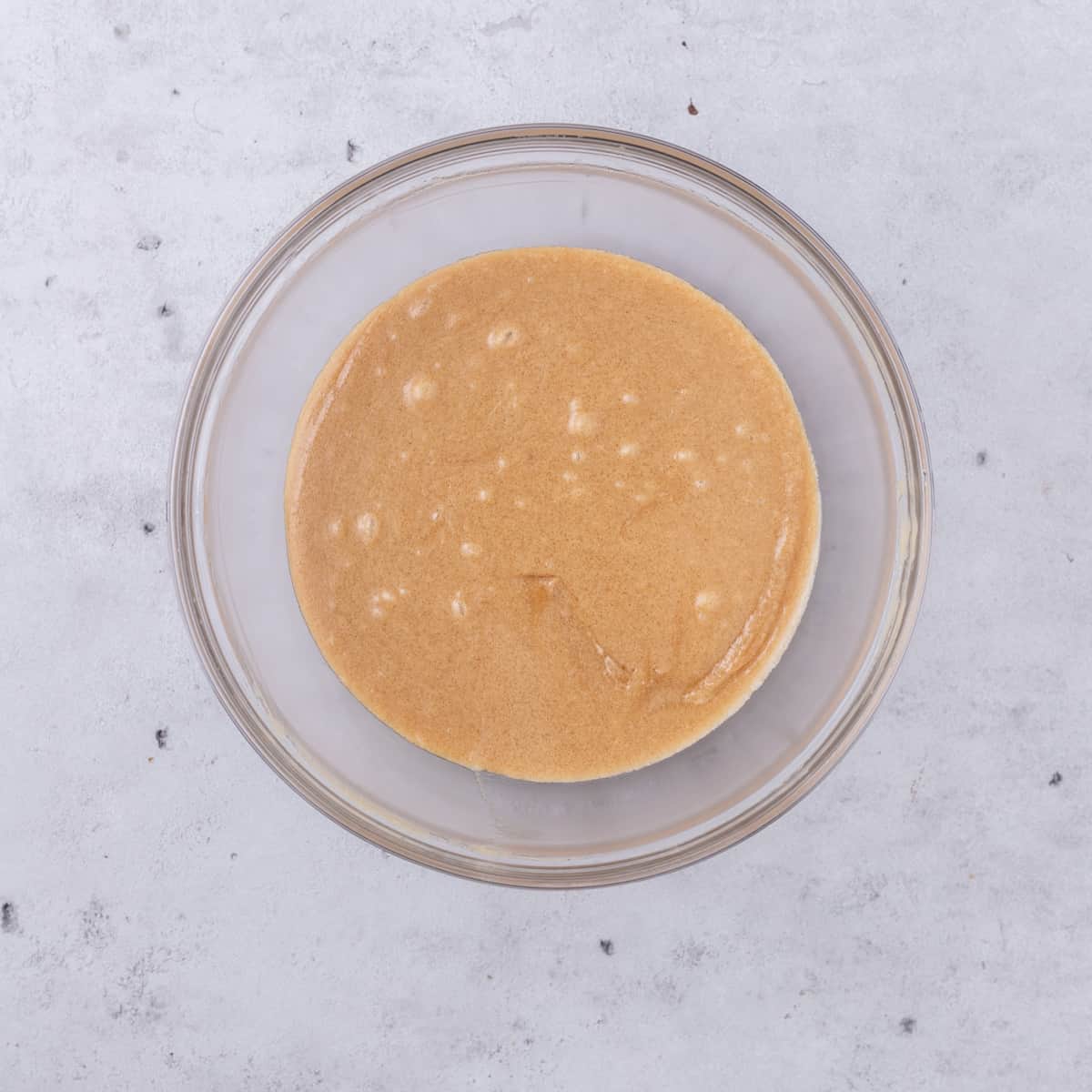 the sugar and wet ingredients combined in a glass bowl on a grey background