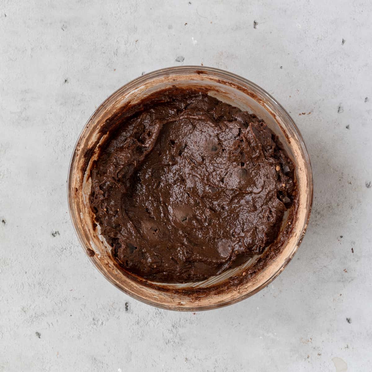 the completed brownie batter in a glass bowl on a grey background