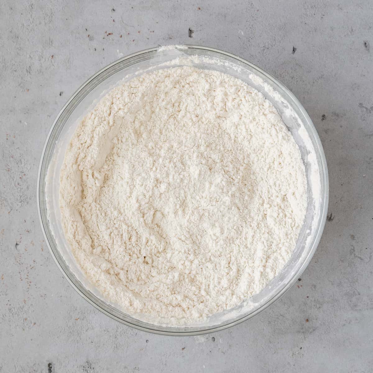 the dry ingredients combined in a glass bowl on a grey background