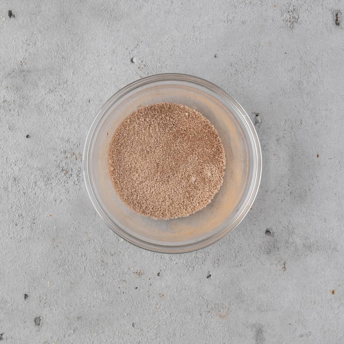 the cinnamon and sugar combined in a glass bowl on a grey background