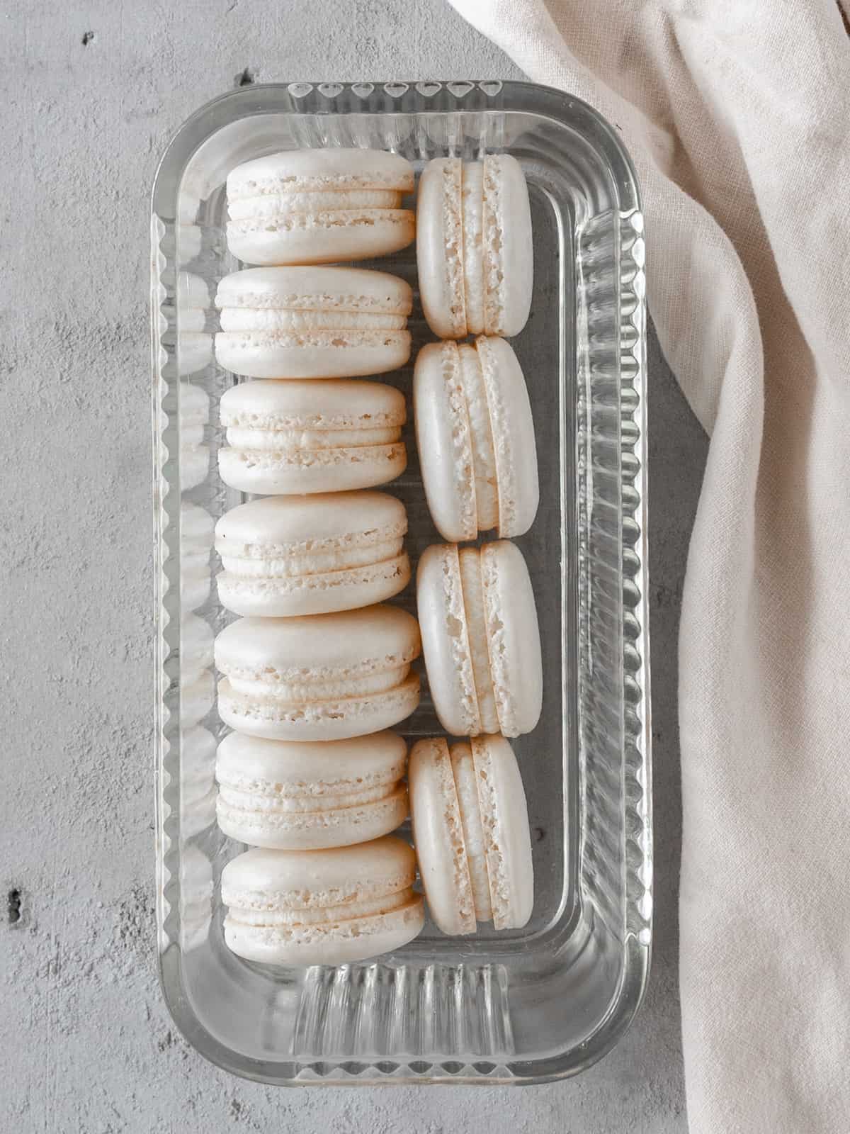two rows of french macarons stacked on their sides in a glass dish