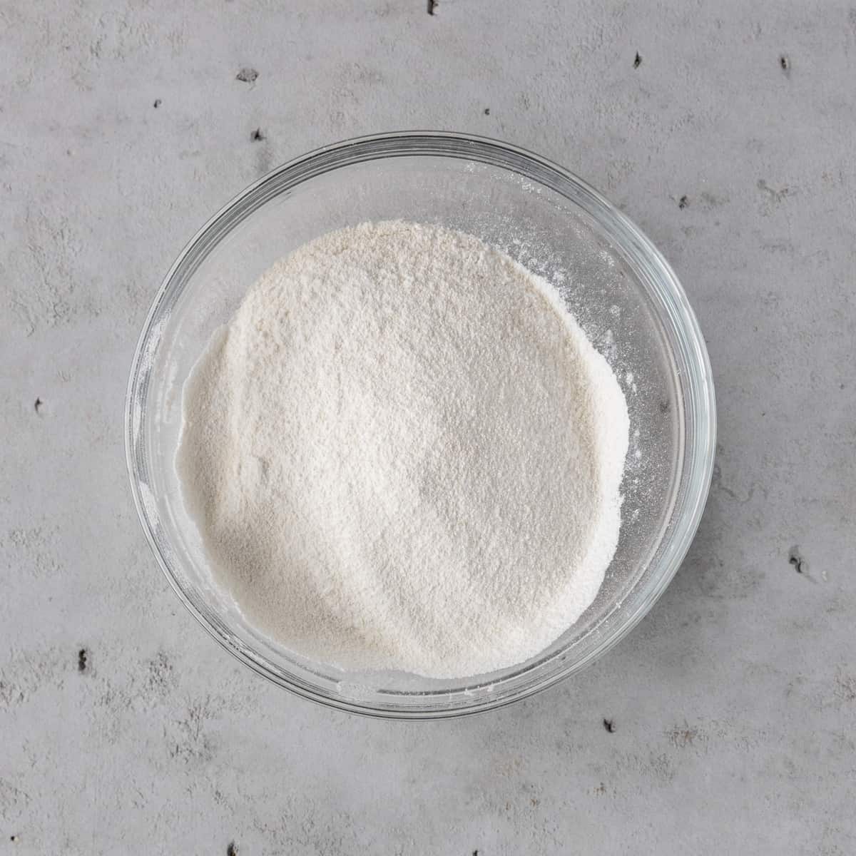 the dry ingredients in a glass bowl on a grey background