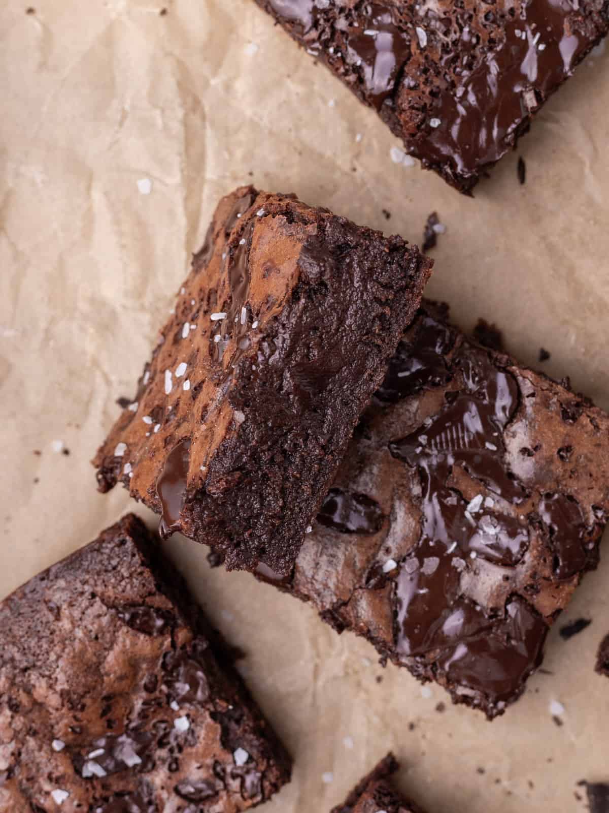 a brownie leaning up against another brownie on a parchment paper.
