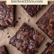 a close up of fudgy brownies sprinkled with salt on parchment paper with fudgy brownies written at the top