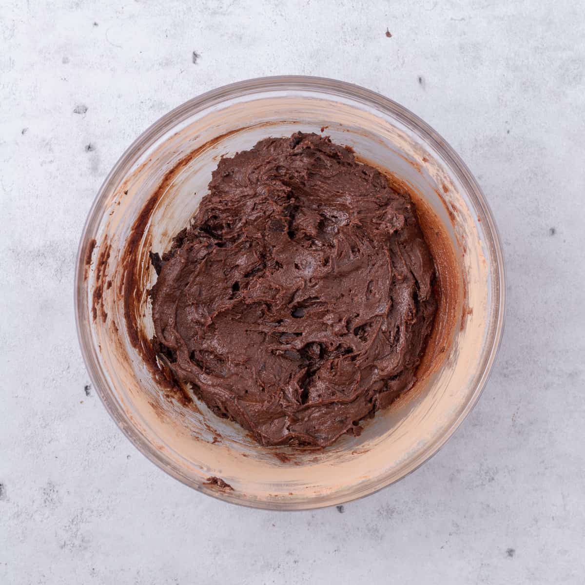 the completed brownie batter in a glass bowl on a grey background