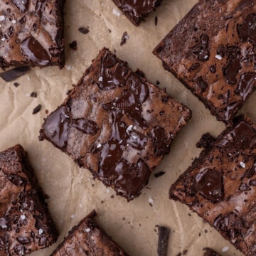 a closeup of fudgy brownies sprinkled with salt on parchment paper