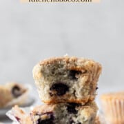 two gluten free blueberry muffins stacked on top of each other, both have a bite out of them