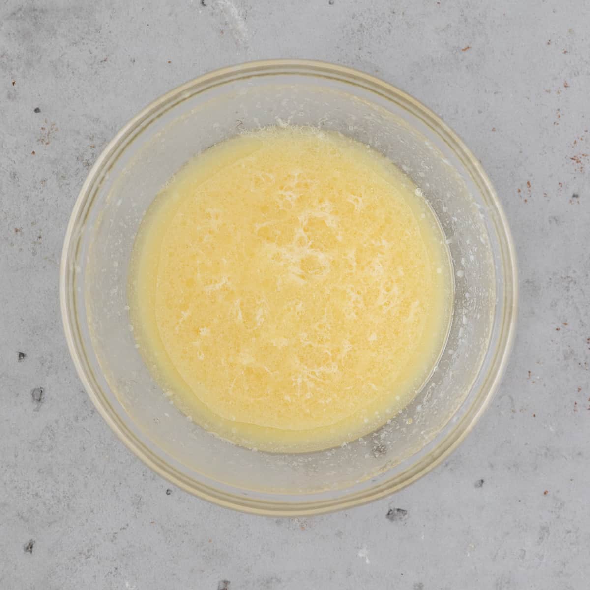 the wet ingredients combined in a glass bowl on a grey background
