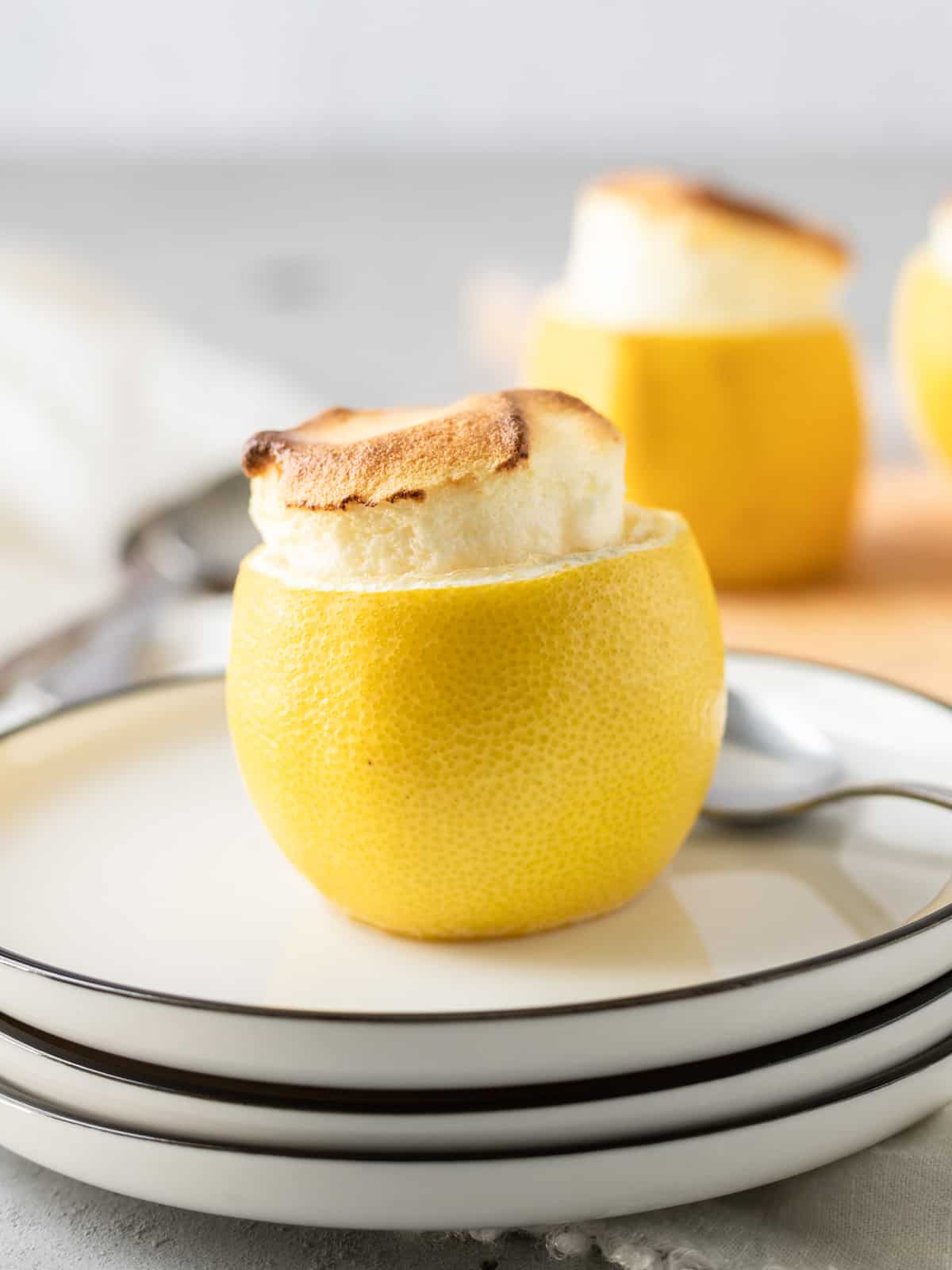 A lemon soufflé on a white plate with other soufflés behind it