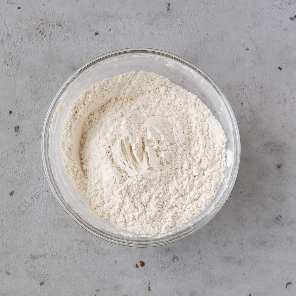 the dry ingredients combined in a glass bowl on grey background