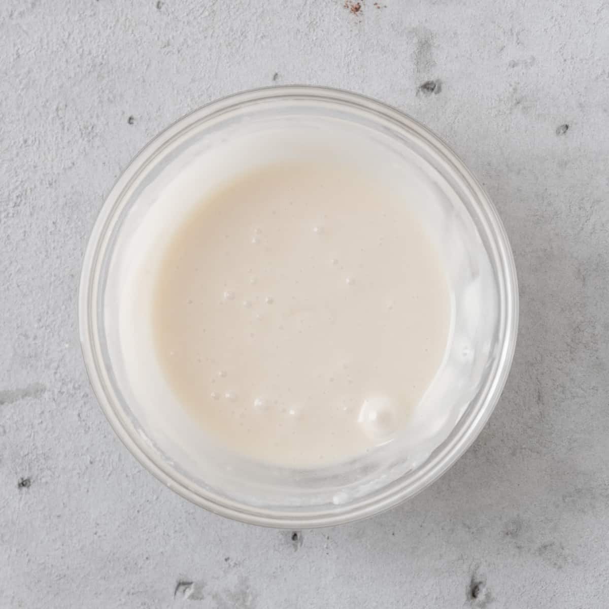 the vanilla glaze in a glass bowl on a grey background