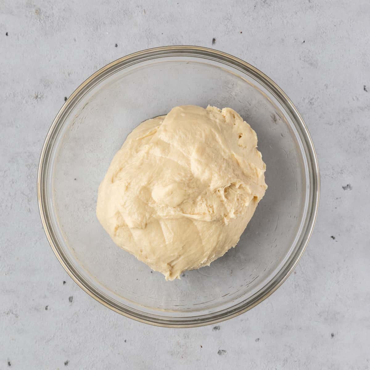 the cinnamon roll dough in a glass bowl before rising