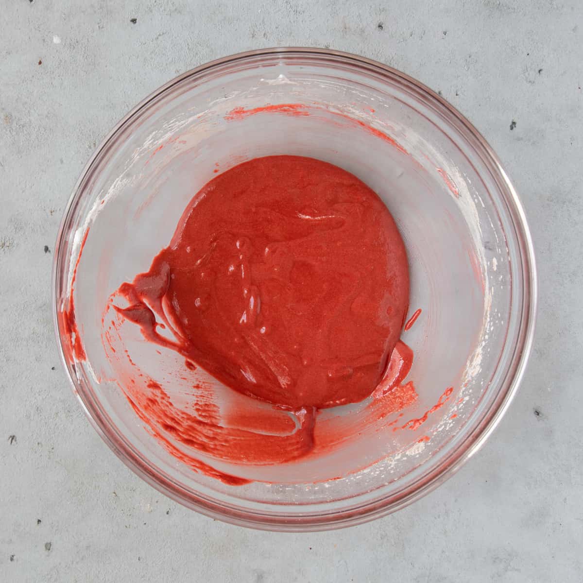 the completed macaron batter in a glass bowl on a grey background