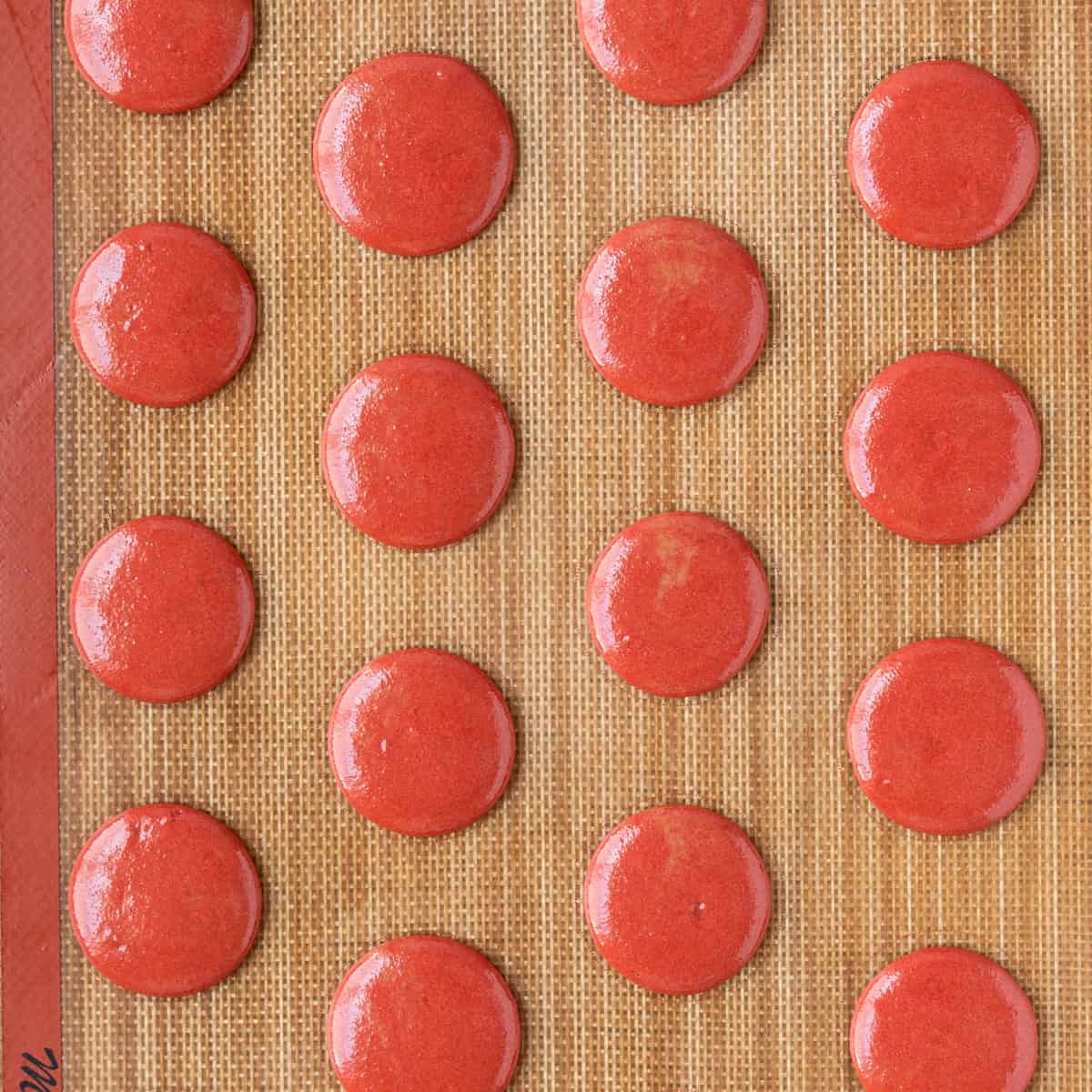 the macarons piped onto a silicone mat