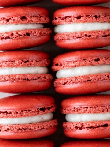 two rows of red velvet macarons on a tan background