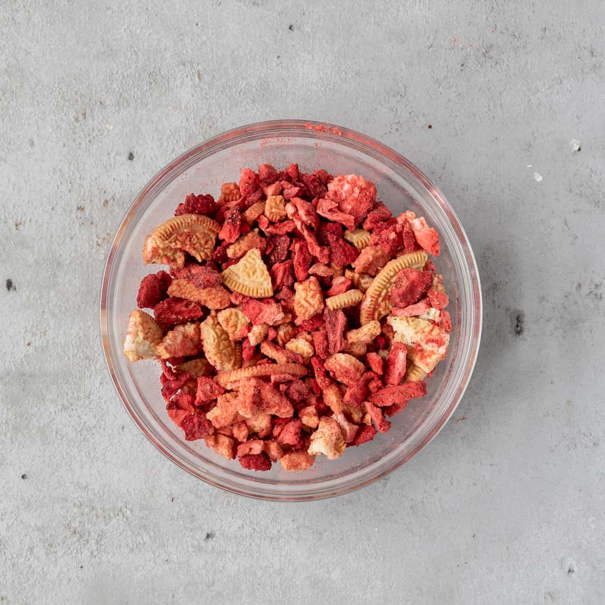 the strawberry crunch combined in a glass bowl on a grey background