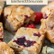 several white chocolate and raspberry blondies in a metal dish. It says white chocolate and raspberry blondies across the top