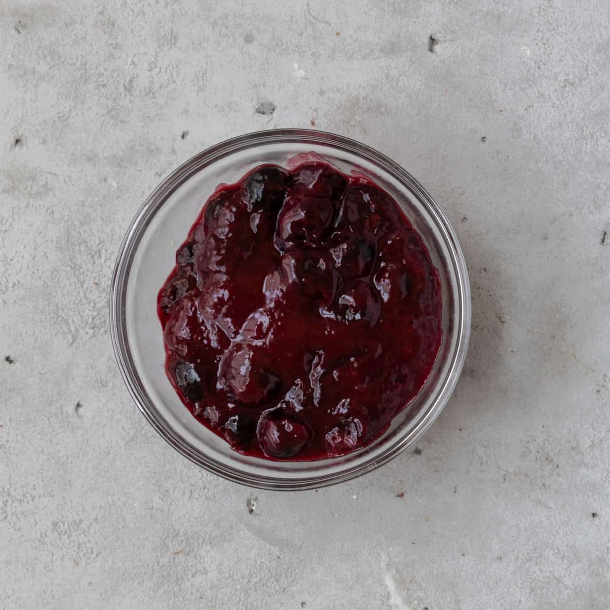 the completed cherry compote in a glass bowl on grey background