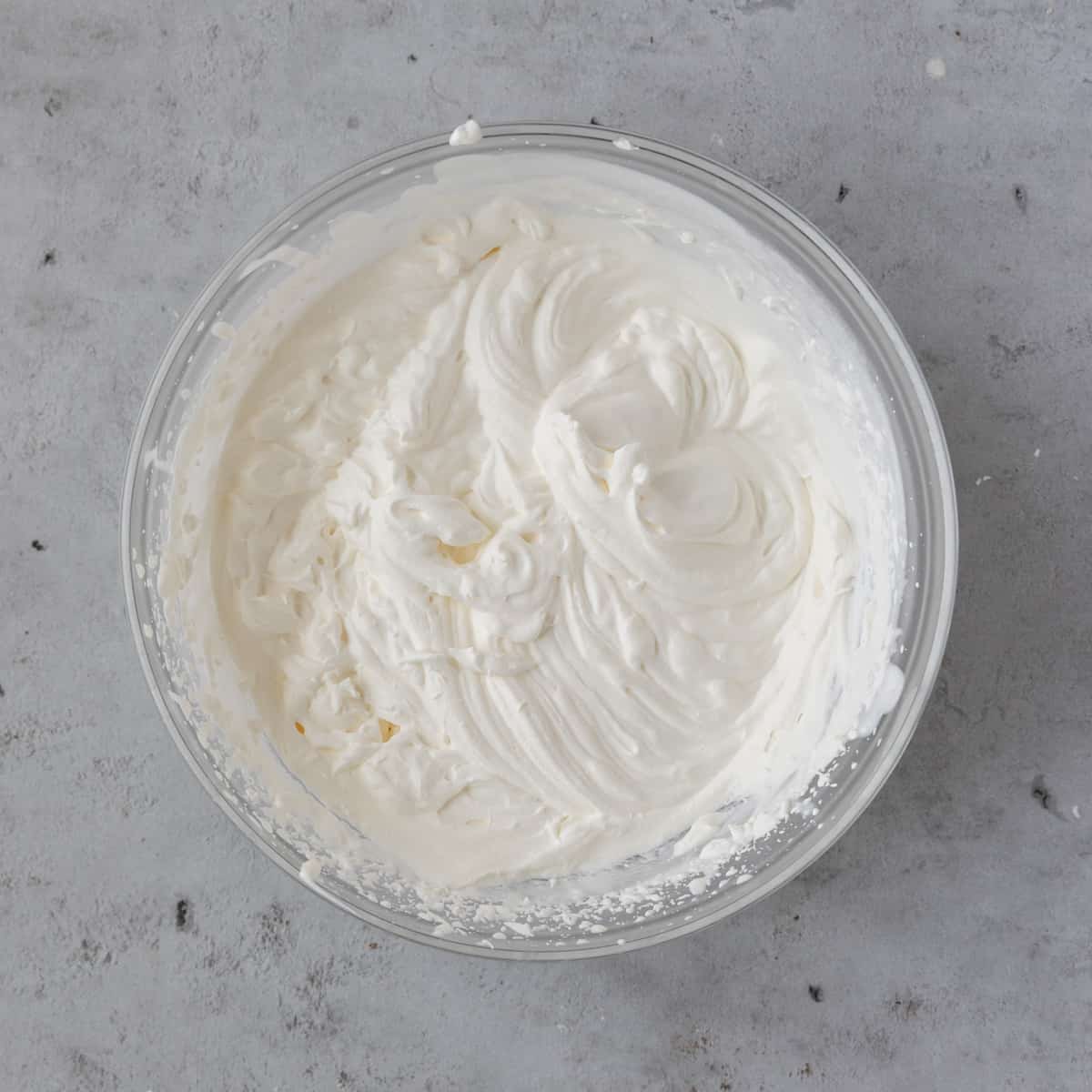 the completed whipped cream in a glass bowl on a grey background