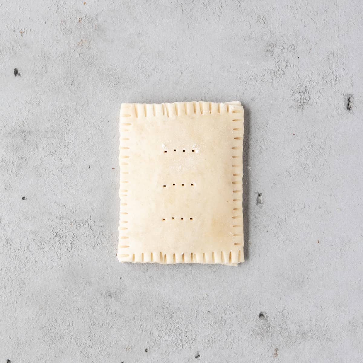 a blueberry pop tart before being baked on a grey background.