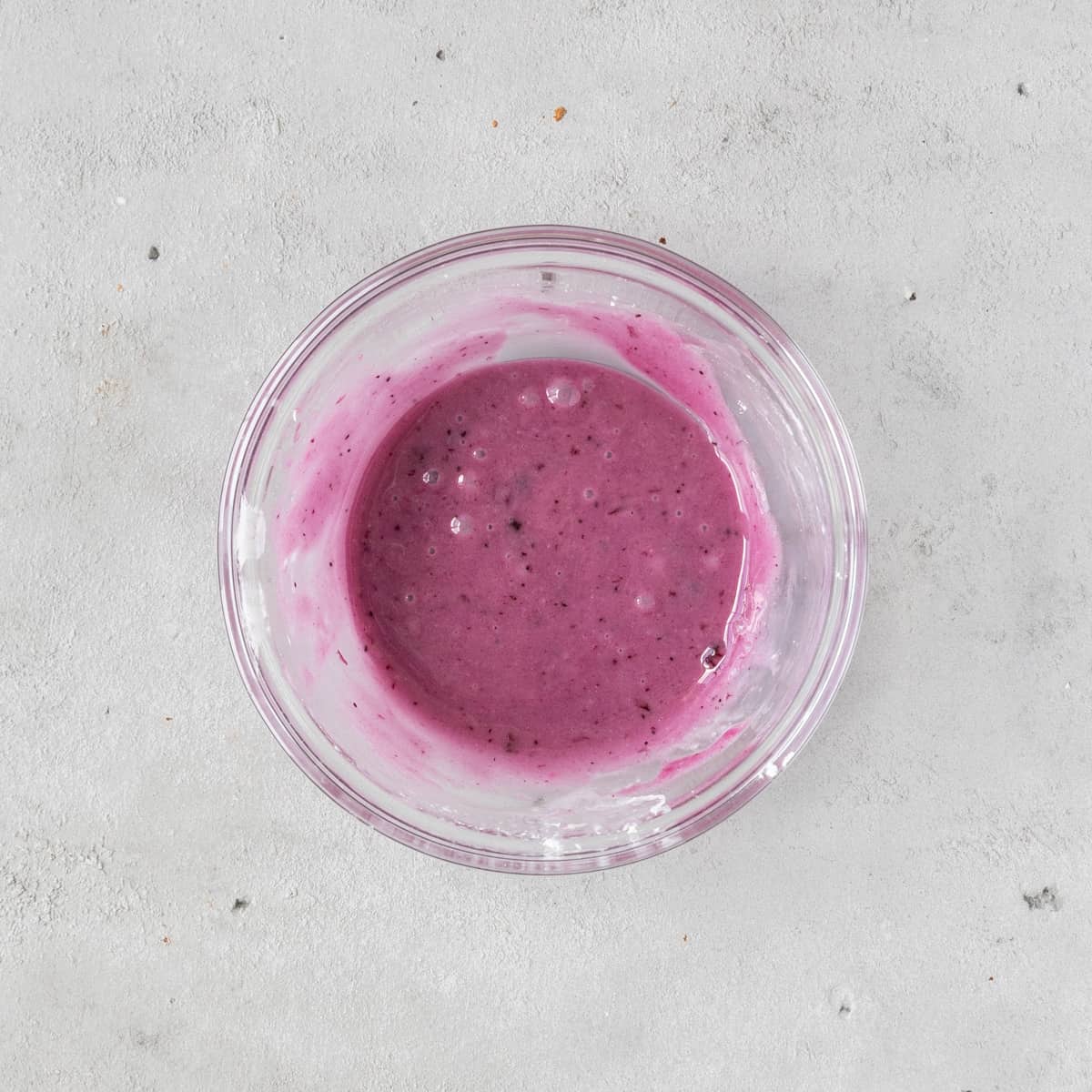 the blueberry glaze in a glass bowl on a grey background.