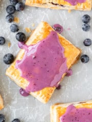 looking down on a blueberry pop tart on parchment paper surrounded by other pop tarts and fresh blueberries.