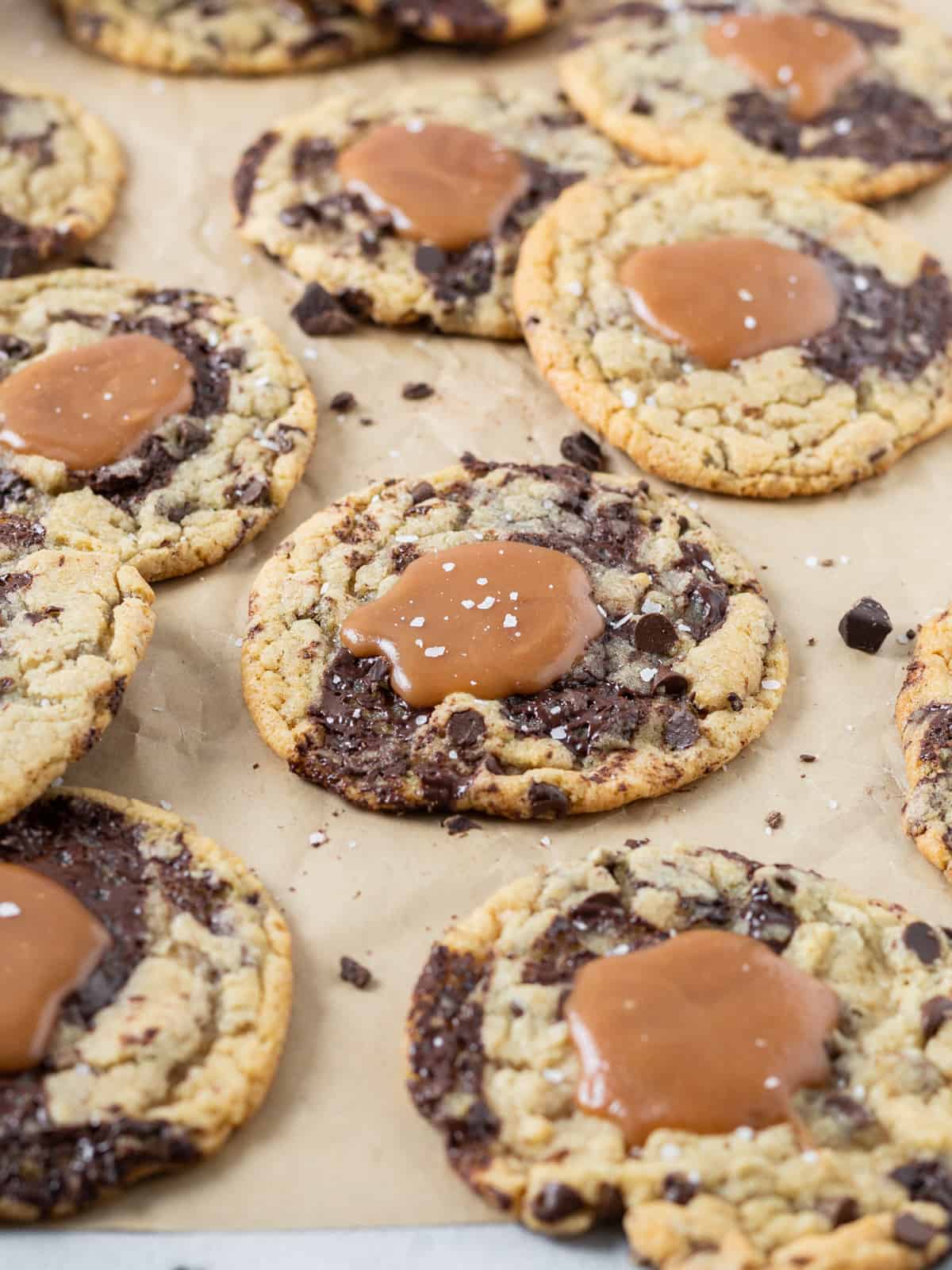 a caramel chocolate chip cookie on parchment paper surrounded by other cookies.