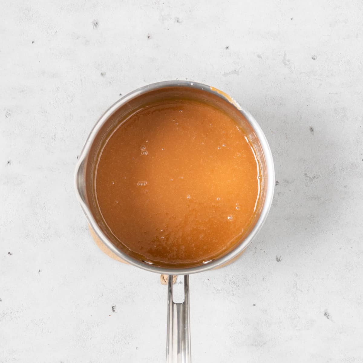 the caramel in a saucepan on a grey background.