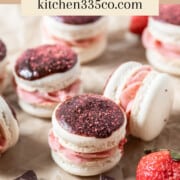 a chocolate strawberry macaron on parchment paper surrounded by other macarons, fresh strawberries, and chunks of chocolate. It says chocolate strawberry macarons across the top.