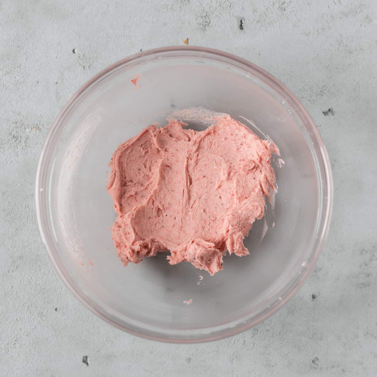 the strawberry american buttercream in a glass bowl on a grey background.