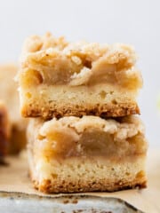 two apple crumble bars stacked on top of each other on a metal pan.