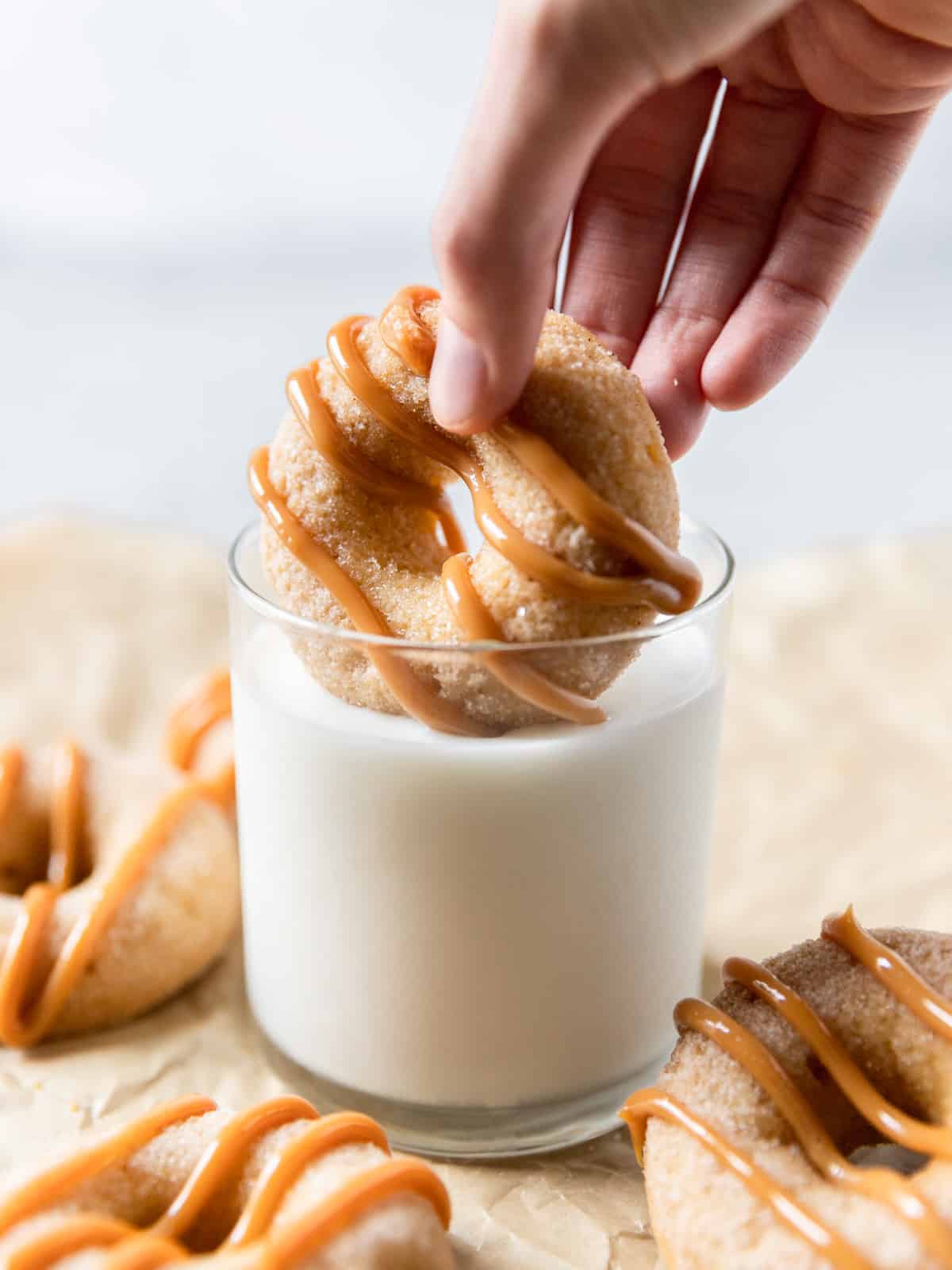 a churro donut being dipped into a glass of milk.