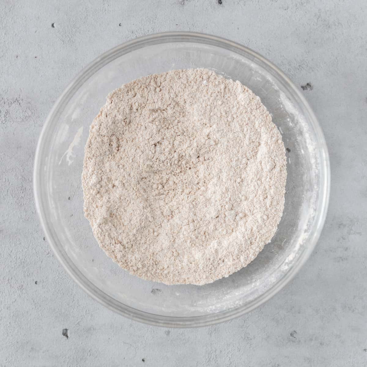 the dry ingredients combined in a glass bowl on a grey background.