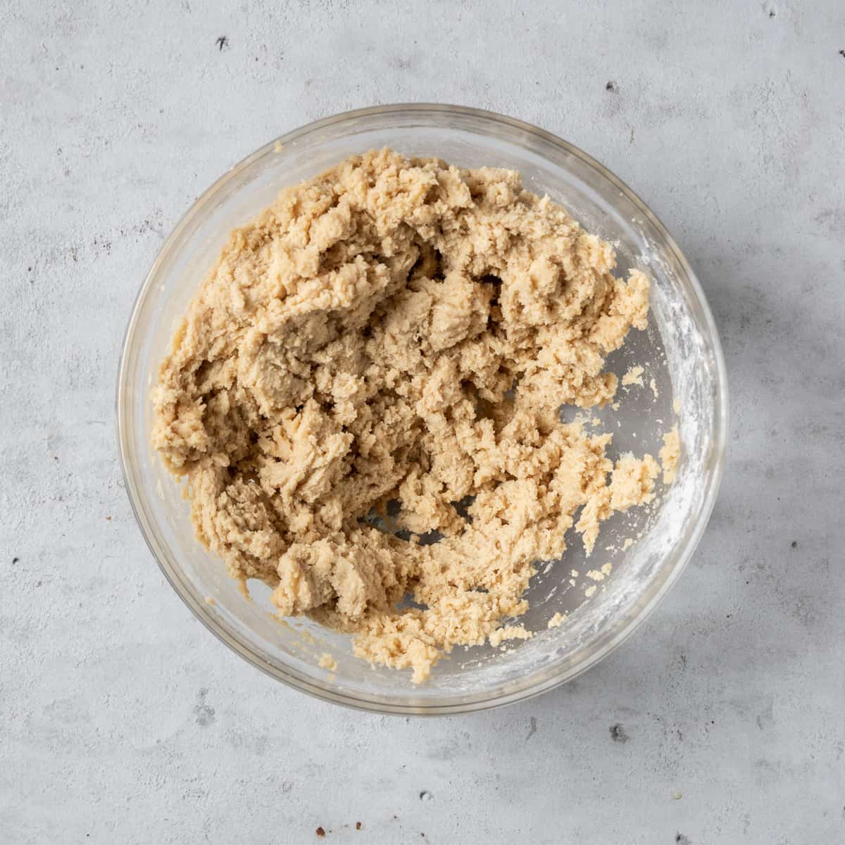 the completed cookie dough in a glass bowl on grey background.